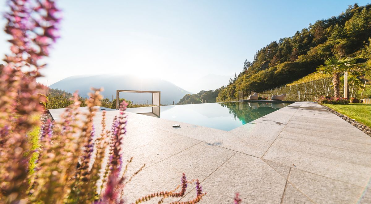 Sonnenuntergang hinter dem Vigiljoch mit Infinity Pool im Vordergrund im Garten des Wellnesshotel Kiendl an der Talstation Meran 2000