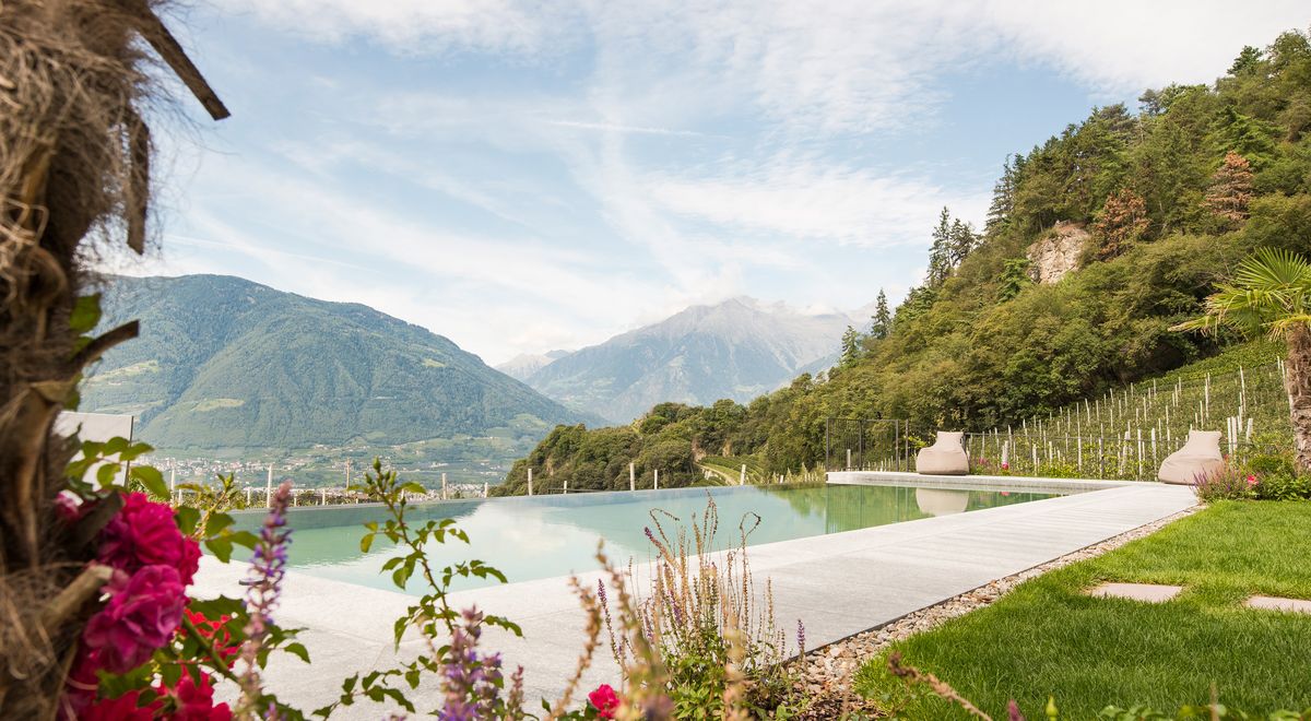 Blühende Blumen, Palmen & Infinity Pool mit Blick auf Meran und umliegende Berge im Wellnesshotel Schenna, Kiendl