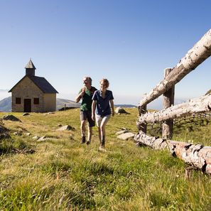 Paar beim Wandern in Südtirol mit Alpiner Kirche im Hintergrund